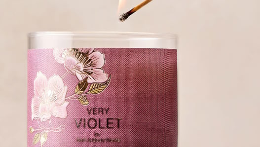 Hand lighting a Very Violet 3-Wick candle